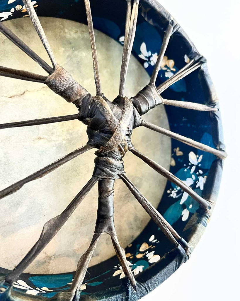Side view of hand-painted Honeysuckle Dream Spirit drum showing deep blue hoop with white and cream floral design by Ingrid Sanchez.