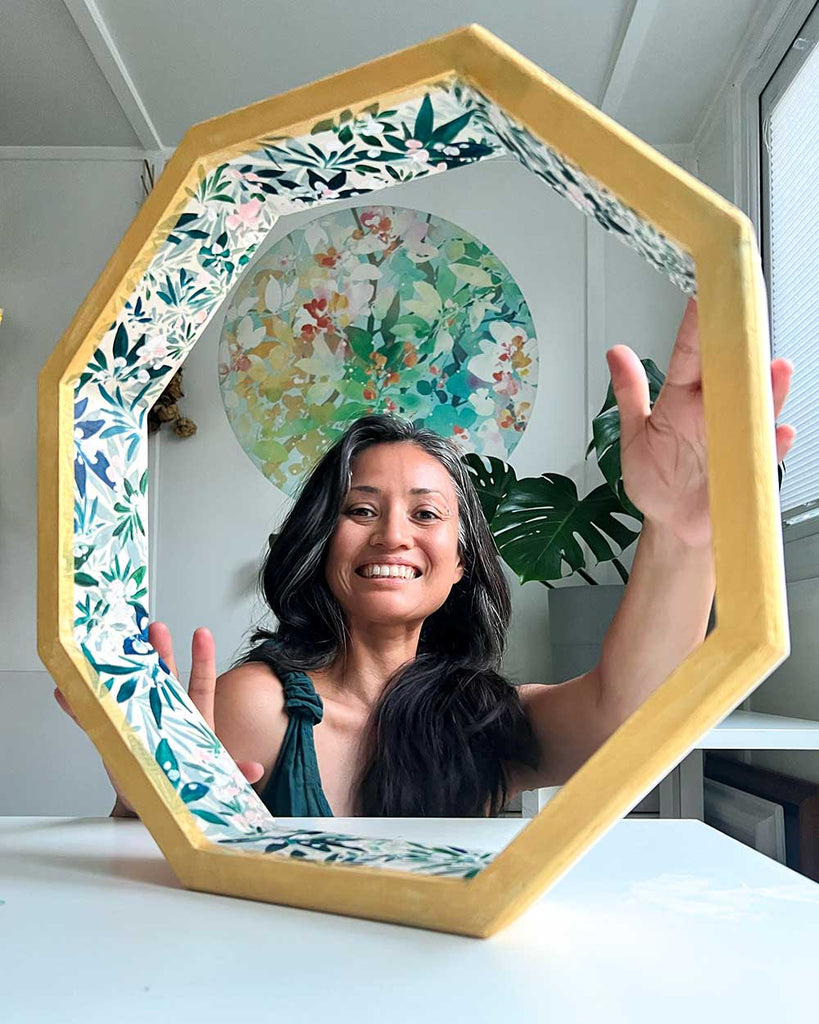 Artist Ingrid Sanchez hand-painting the hoop of a shamanic drum during the creation process in her London studio