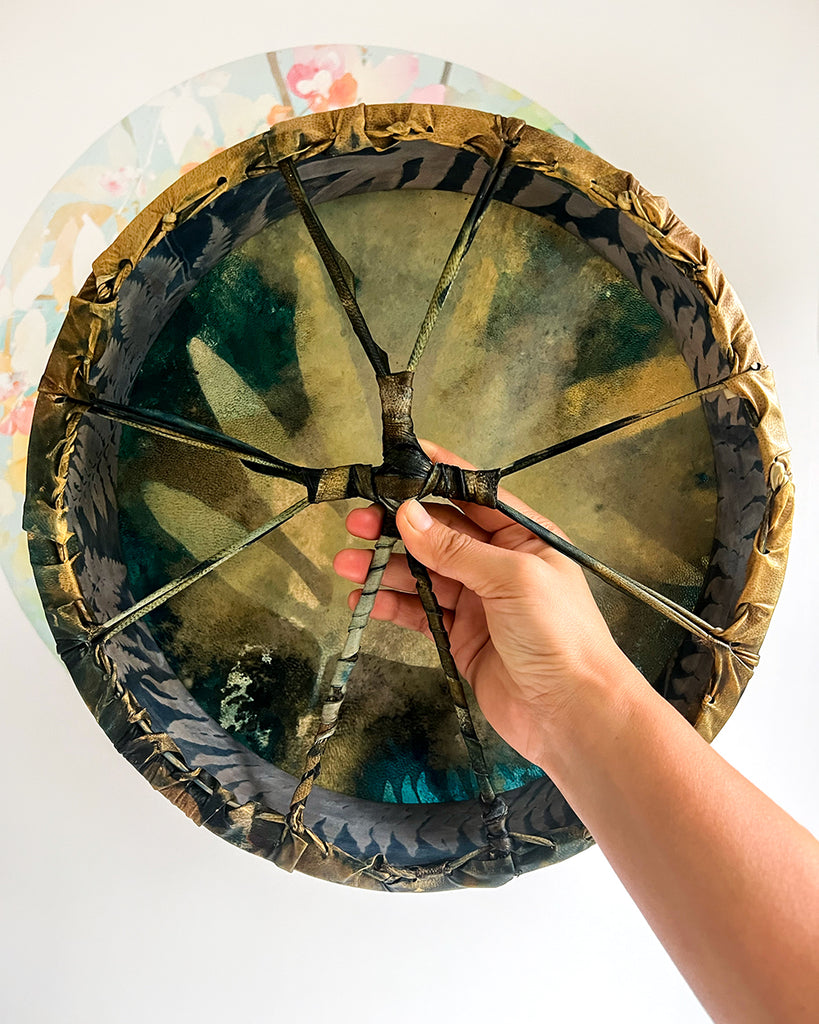 Handmade shamanic drum showing willow wood hoop wrapped in hand-painted silk with rim lacing.