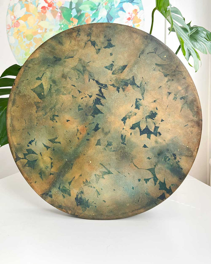 Gaia’s Heartbeat 16-inch shamanic drum by Ingrid Sanchez, floral pattern and earthy tones of green, deep blue, and soft gold on Gaia’s Heartbeat shamanic drum.