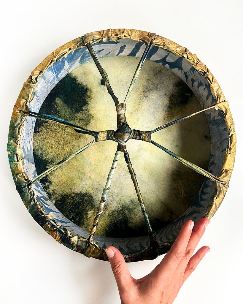 Artist-made ceremonial drum with natural materials, blue cyanotype artwork, and star-like gold detailing.