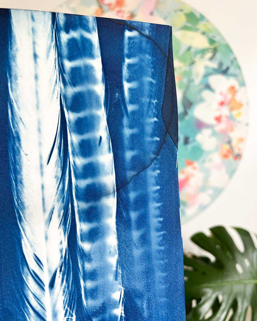 Blue art with white patterns against a floral and green leaf background.