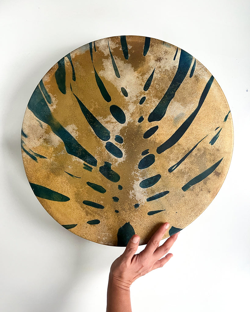 Artist-made shamanic drum featuring bold monstera imprint and decorative braid on the back.