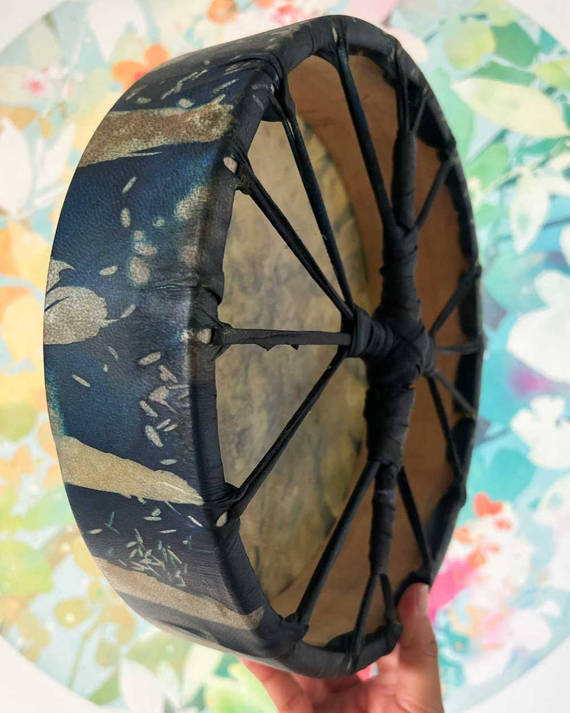 Hand holding Feather Spirit shamanic drum, showing its size, deep colors, and handmade craftsmanship.