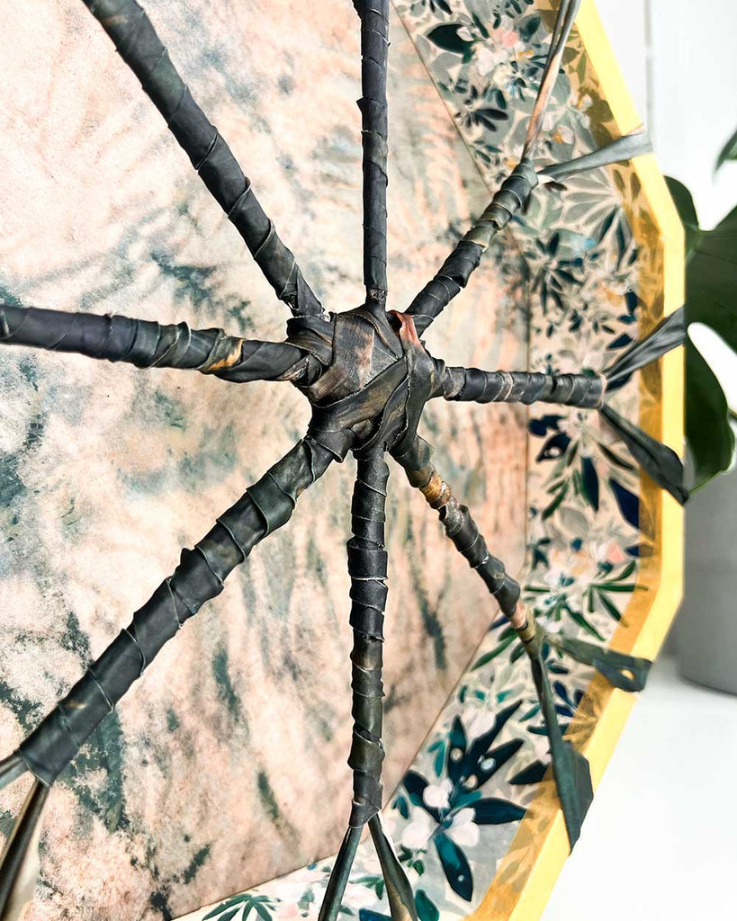 Detail of cyanotype-printed deer hide featuring ferns and botanical patterns in green and pink on handmade shamanic drum