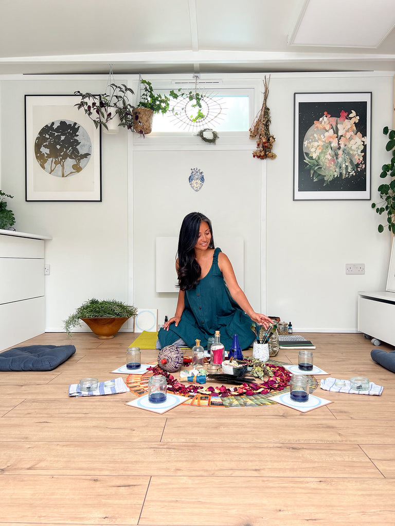 Ingrid Sanchez in a teal dress sitting on the floor in her London studio, ready for a women's circle.