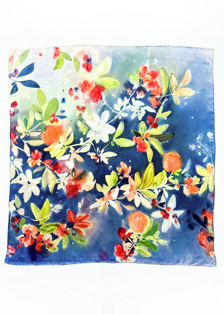 ‘Citrus Passion Grove’ is an original, one-of-a-kind piece painted by hand using vibrant dyes on 100% silk. This design is a celebration of nature’s vibrancy, featuring glowing citrus tones of orange, red, and soft white blossoms against a rich blue backdrop. Hints of lush green leaves weave through the composition, creating a lively and fresh atmosphere. Ingrid Sanchez, 2025, CreativeIngrid.