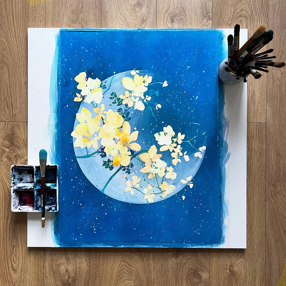 White moon filled with yellow flowers against a vivid blue sky. Ingrid Sanchez, original moon art. London 2023.