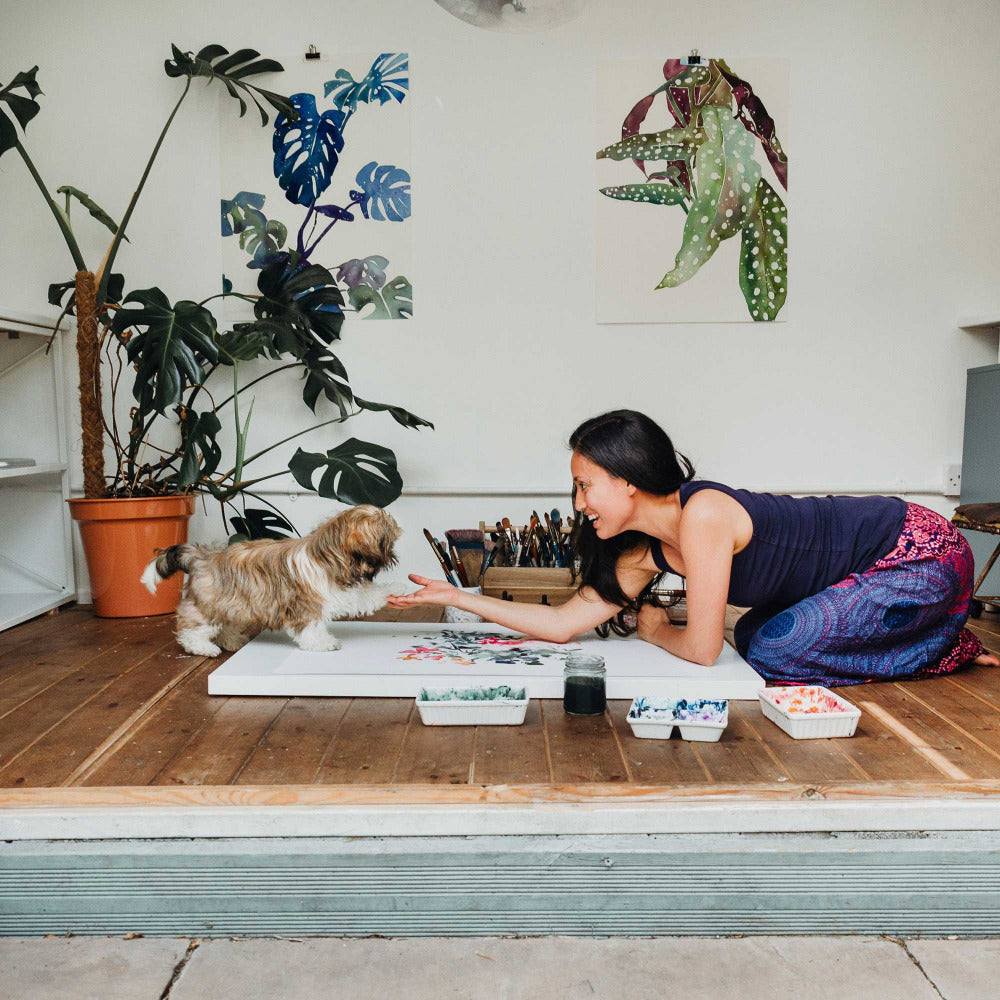 Artist Ingrid Sanchez and her Shih Tzu, the 'studio assistant' painting large botanical paintings in her art studio based in West London. Photo by Azu Morales, 2021.